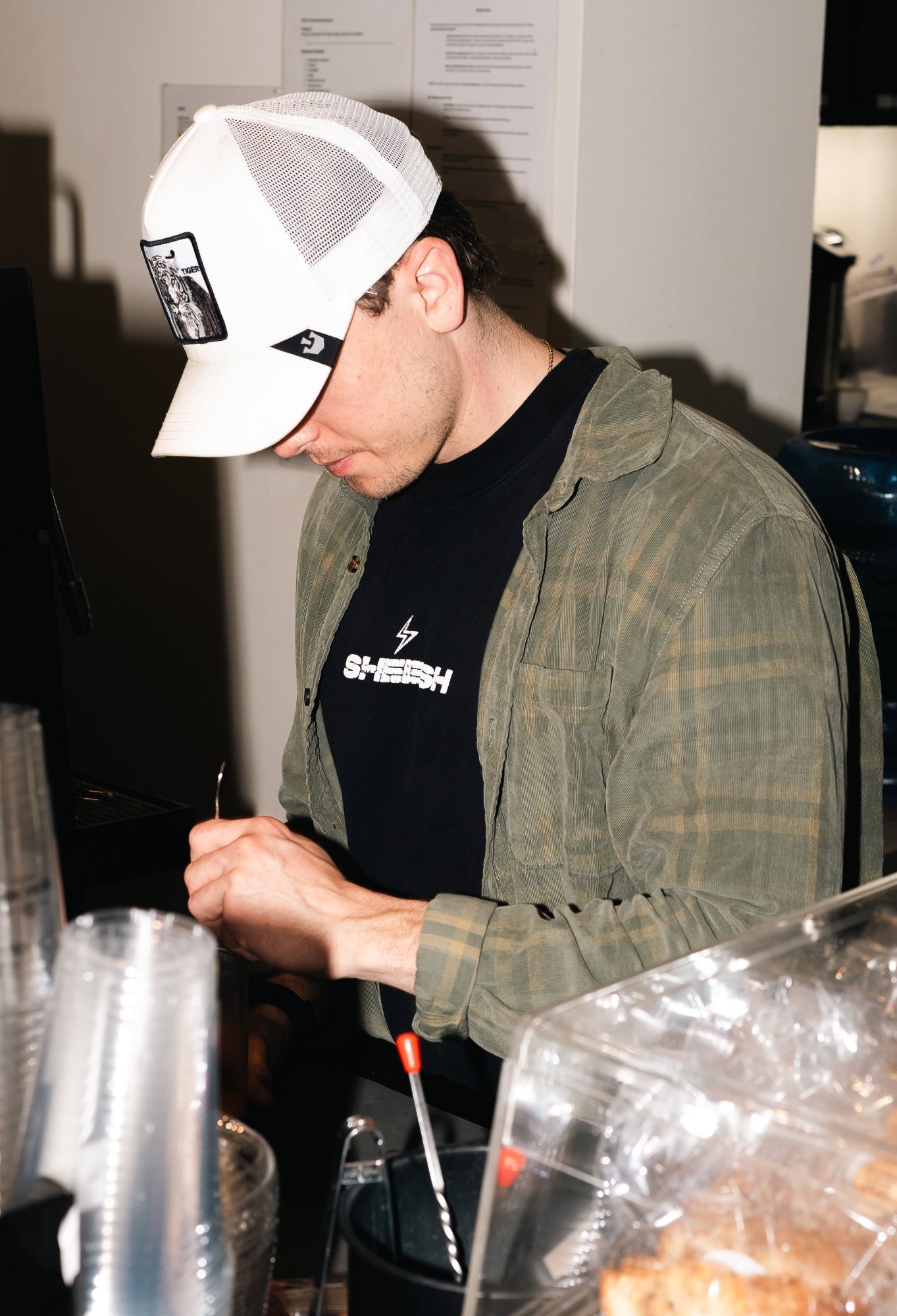 Person working behind a counter with pastries and a coffee machine in the background